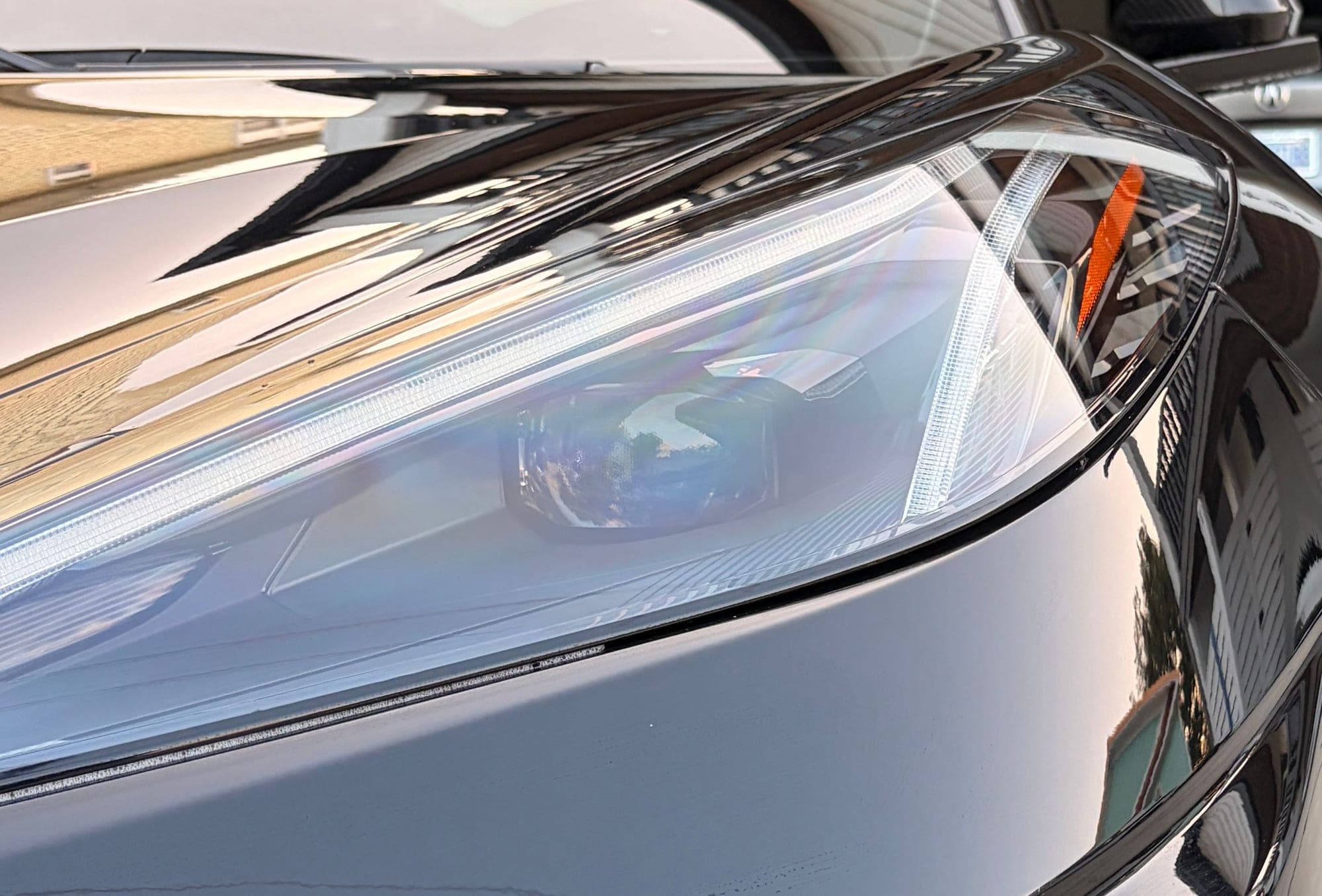 Close-up of the Corvette's driver-side headlight and hood line, glass-like gloss finish