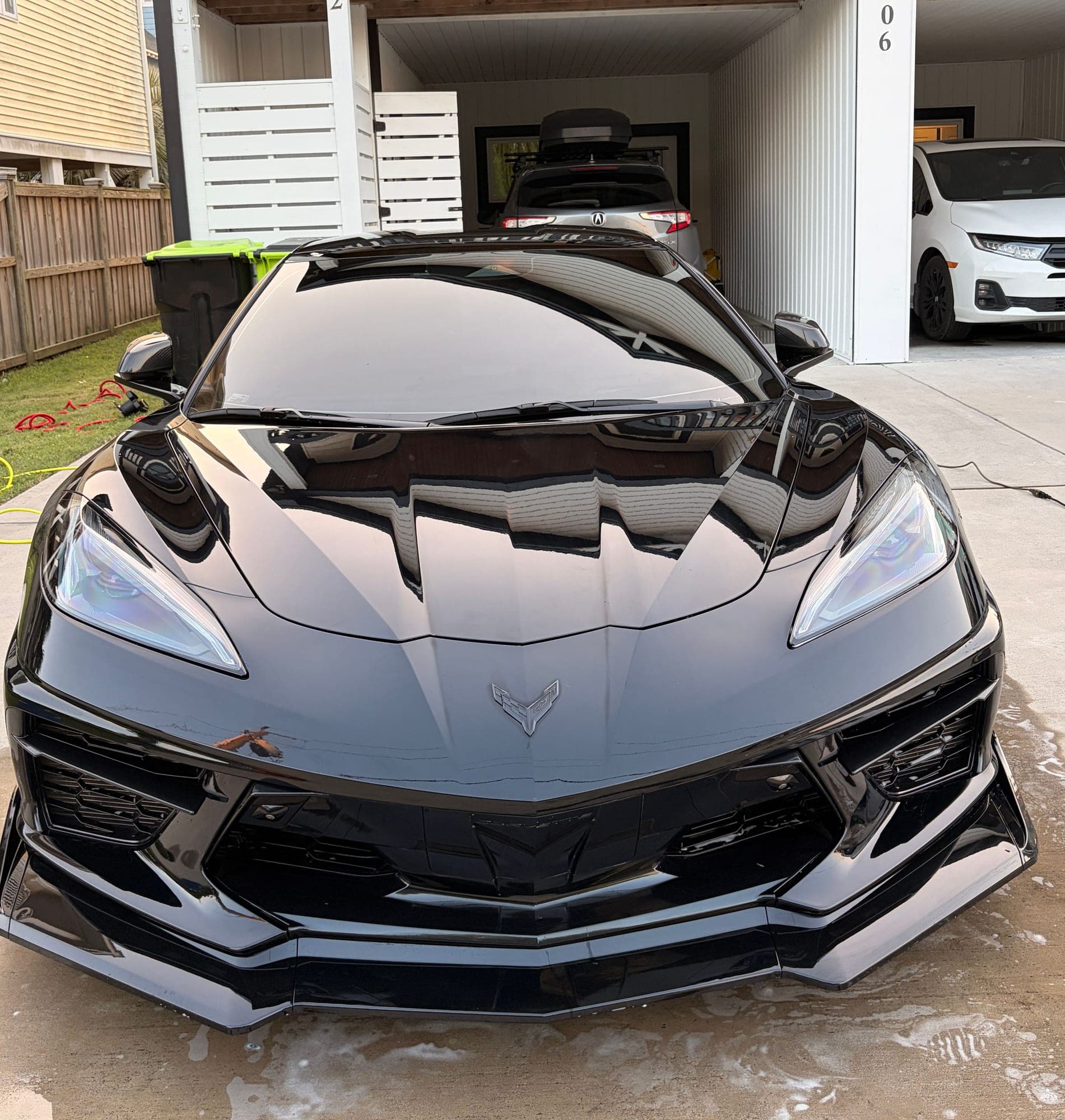 Black Chevrolet Corvette C8 nose-on after a full detail, paint reflecting like a mirror